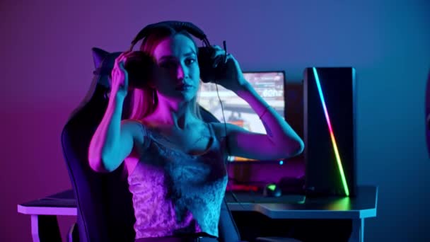 Tatuoitu gamer tyttö istuu PC - laittaa hänen kuulokkeet ja kääntyy näytön - Materiaali, video