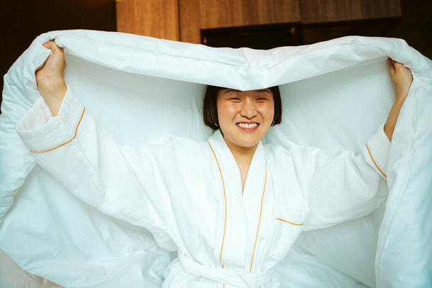Asian short hair woman playing with white blanket in bedroom. - Photo, Image
