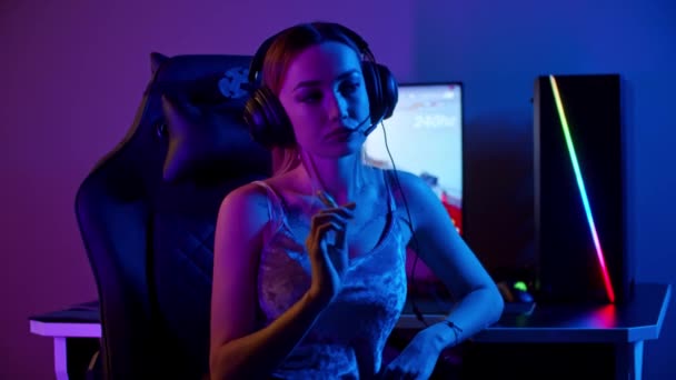 Татуированная девушка-геймер сидит у компьютера и держит леденец - Кадры, видео