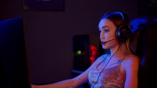 Tetovaná hráčka sedí u PC v neonovém herním klubu a hraje hru - Záběry, video