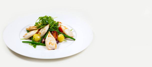 A beautifully decorated meal with chicken, vegetables, and green on a white plate - 写真・画像