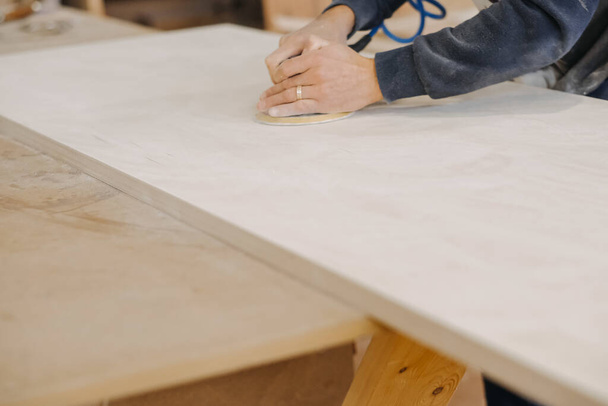 A closeup shot of a craftsman polishing a wood plank - Фото, зображення