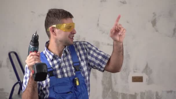 Grappige vrolijke en vrolijke mannelijke bouwer of arbeider dansen op de achtergrond van reparaties in het huis, slow motion - Video