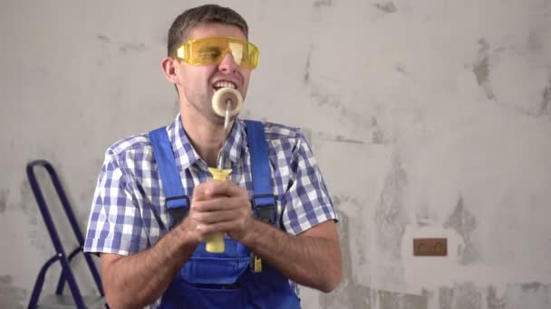 Joyeux et heureux constructeur masculin ou travailleur chante sur le fond de réparations dans la maison, au ralenti - Séquence, vidéo
