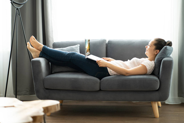 Pohodlná žena s notebookem na gauči doma - Fotografie, Obrázek