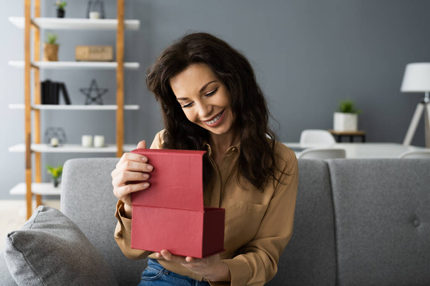 Happy Woman Sitting At Home Opening Gift - Foto, Bild