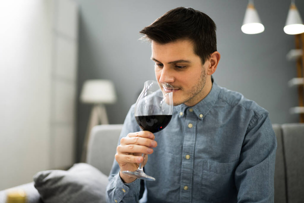 Homme buvant du vin rouge en vidéoconférence à la maison - Photo, image