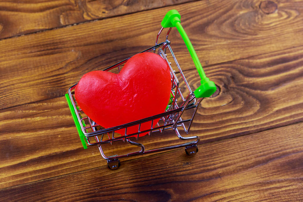 Winkelwagen met groot rood hart op houten achtergrond. Valentijnsdag concept - Foto, afbeelding