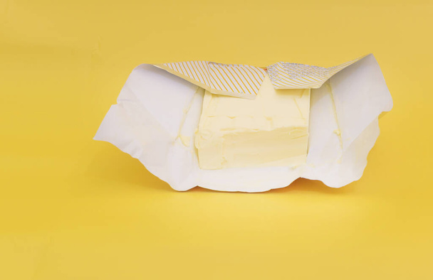 Butter on a yellow background, the benefits of butter - 写真・画像