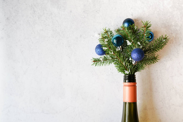 Botella de champán con árbol de Navidad y decoraciones de bolas azules sobre fondo gris. Acostado. Concepto de fiesta. espacio de copia - Foto, Imagen