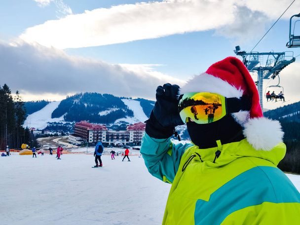 szczęśliwy człowiek w stroju narciarskim z Mikołajem czerwony kapelusz Bożego Narodzenia w zimie góry wzgórza przestrzeń kopia - Zdjęcie, obraz