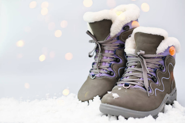 Pair of woman suede grey boots on snow in winter sunny day. - Foto, Bild