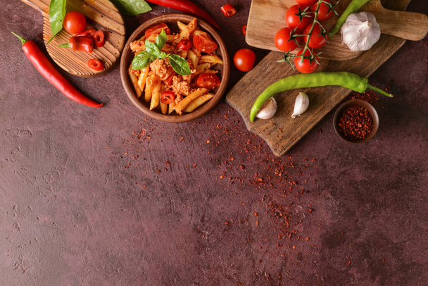 Schaal van penne pasta met tomatensaus op kleur achtergrond - Foto, afbeelding