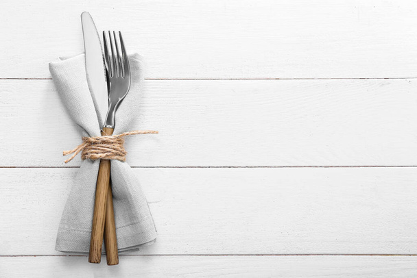 Cutlery and napkin on light wooden background - Photo, Image