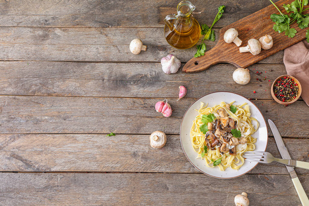 Talíř z chutných těstovin s kuřecím masem a houbami na dřevěném stole - Fotografie, Obrázek