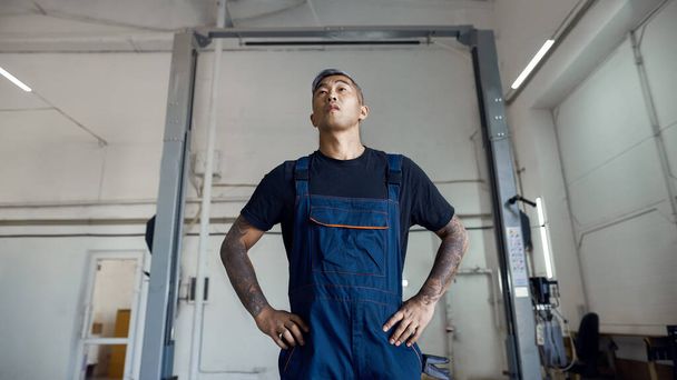 Young asian worker in car service station uniform - Foto, Bild