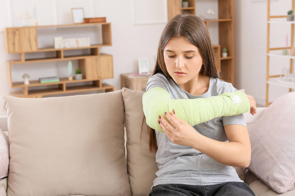 Junge Frau mit gebrochenem Arm zu Hause - Foto, Bild