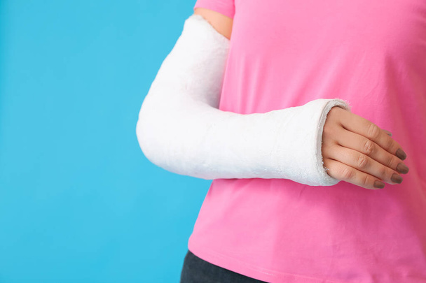 Junge Frau mit gebrochenem Arm auf farbigem Hintergrund, Nahaufnahme - Foto, Bild