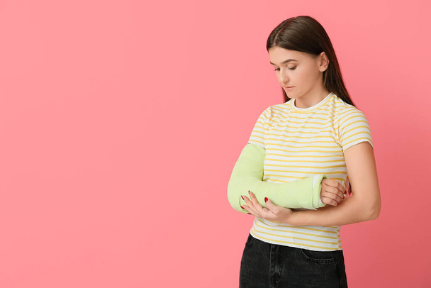 Junge Frau mit gebrochenem Arm auf farbigem Hintergrund - Foto, Bild