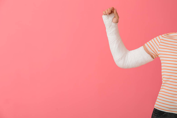 Giovane donna con braccio rotto su sfondo colore - Foto, immagini