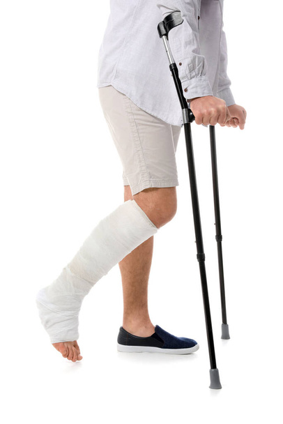 Nuori mies, jolla on murtunut jalka valkoisella taustalla - Valokuva, kuva