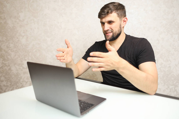 ein Mann im schwarzen T-Shirt sitzt an einem Laptop - Foto, Bild