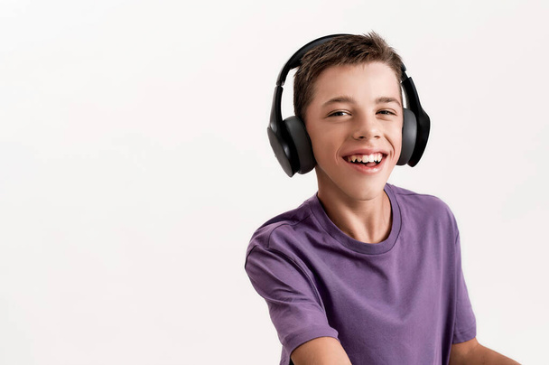 Close up portrait of happy teenaged disabled boy with cerebral palsy in headphones smiling at camera, using his walker isolated over white background - Photo, Image