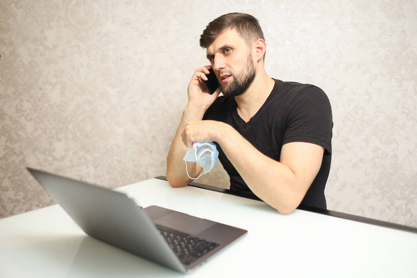 osoba v izolaci pracuje doma na notebooku a mluví po telefonu - Fotografie, Obrázek