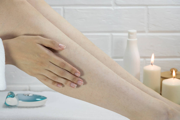 Cuidado de la piel, cuerpo. Preparación de las piernas para el procedimiento de depilación. Cabello en las piernas de las mujeres. Cuerpo positivo, autoaceptación, feminismo. Aplica la crema, masajea. Patas de fresa, queratosis. Relajación - Foto, Imagen