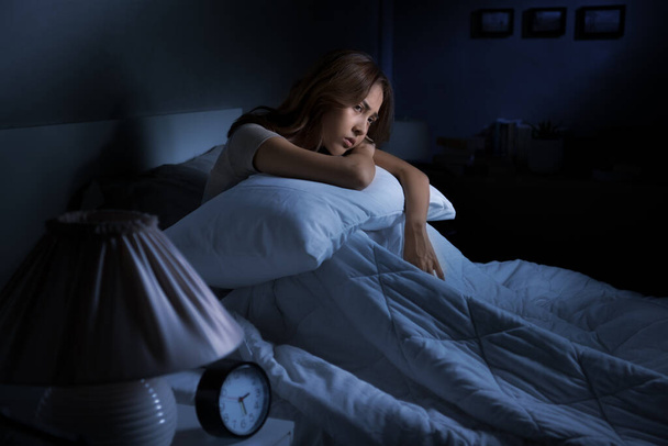 Masentunut nuori aasialainen nainen istuu sängyssä ei voi nukkua unettomuudesta - Valokuva, kuva