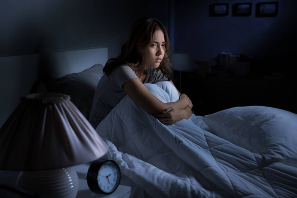 przygnębiona młoda Azjatka siedząca w łóżku nie może spać z bezsenności - Zdjęcie, obraz
