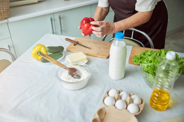 台所で夕食を調理しながら野菜を準備する老婦人 - 写真・画像
