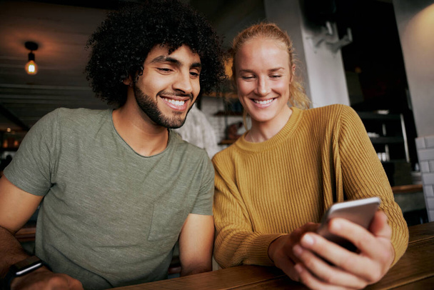 Portrait of happy couple using smartphone and smiling while sitting and relaxing in cafe - Fotoğraf, Görsel