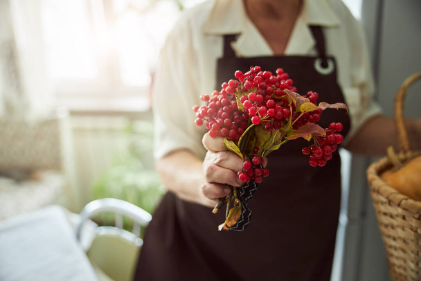 Old woman in apron holding red berries - Fotoğraf, Görsel