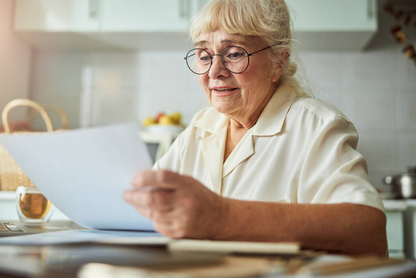 Nice old woman studying documents at home - Foto, Imagem