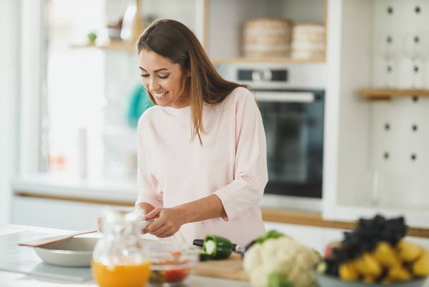 Foto de una mujer joven preparando una comida saludable en la estufa de su cocina. - Foto, imagen