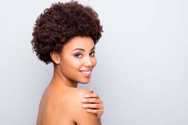Portret uroczej afro amerykańskiej dziewczyny cieszyć zabieg pielęgnacji skóry nawilżenie dotyka ramion jak nieskazitelny błyszczący estetyczny wellness idealny idealny skóra odizolowany szary kolor tła - Zdjęcie, obraz