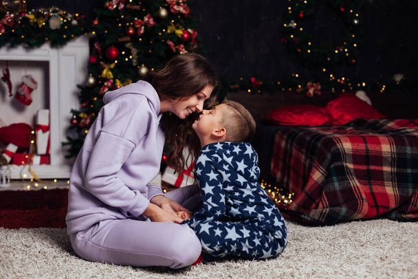 Mom and son at Christmas tree lights garland gifts new year - Foto, Imagem