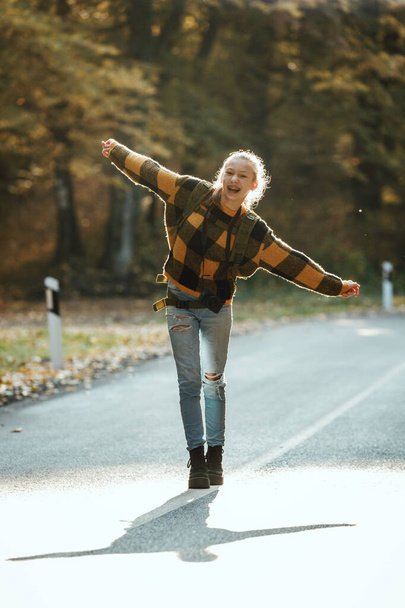 Girato di una ragazza adolescente divertirsi durante la passeggiata attraverso la foresta in autunno. - Foto, immagini