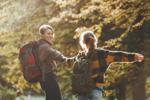 Tourné d'une adolescente et de sa mère s'amusant pendant la promenade ensemble à travers la forêt en automne. - Photo, image
