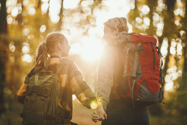 Фотография девочки-подростка и ее мамы, идущих вместе по лесу осенью. - Фото, изображение