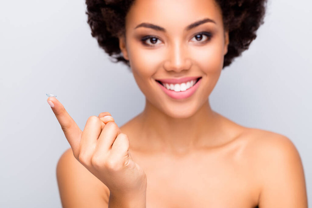 Close up photo of joyful afro american girl visit optician recommend contact lens hold index finger isolated over grey color background - Foto, Imagen