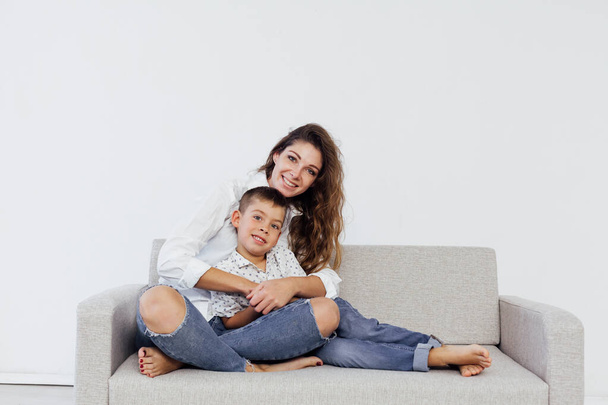 Mom and young son sit at home on a white sofa - Fotoğraf, Görsel