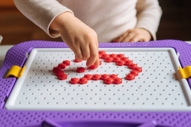 Niño está jugando con rompecabezas de mosaico en casa. Juego creativo para niños para el desarrollo temprano y habilidades motoras finas. - Foto, imagen