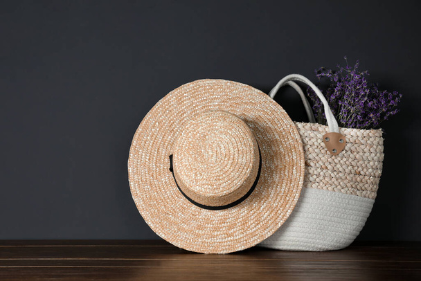 Straw hat and bag with flowers on wooden table - Photo, image