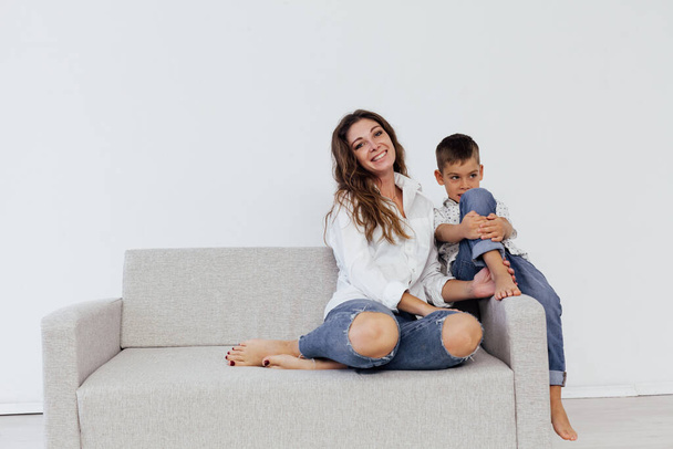 Mom and young son sit at home on a white sofa - Foto, Bild