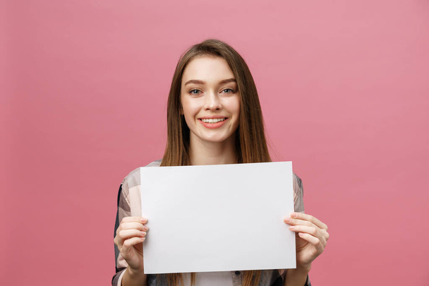 Close up portrait of positive laughing woman smiling and holding white big mockup poster isolated on pink background - Zdjęcie, obraz