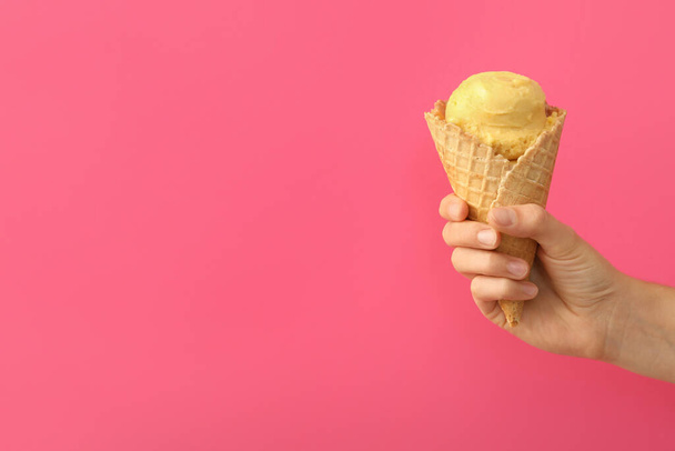 Pembe arka planda lezzetli sarı dondurmalı waffle külahı tutan kadın, yakın plan. Metin için boşluk - Fotoğraf, Görsel