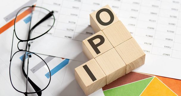 Инициативное публичное предложение IPO, написанное на деревянном кубе на графиках - Фото, изображение