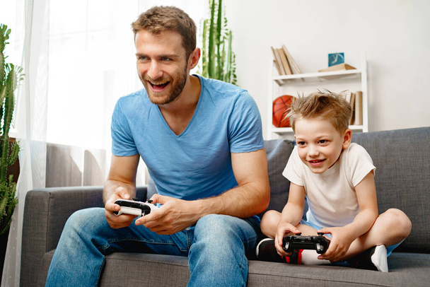 Father and his little son playing video games together at home - Photo, Image